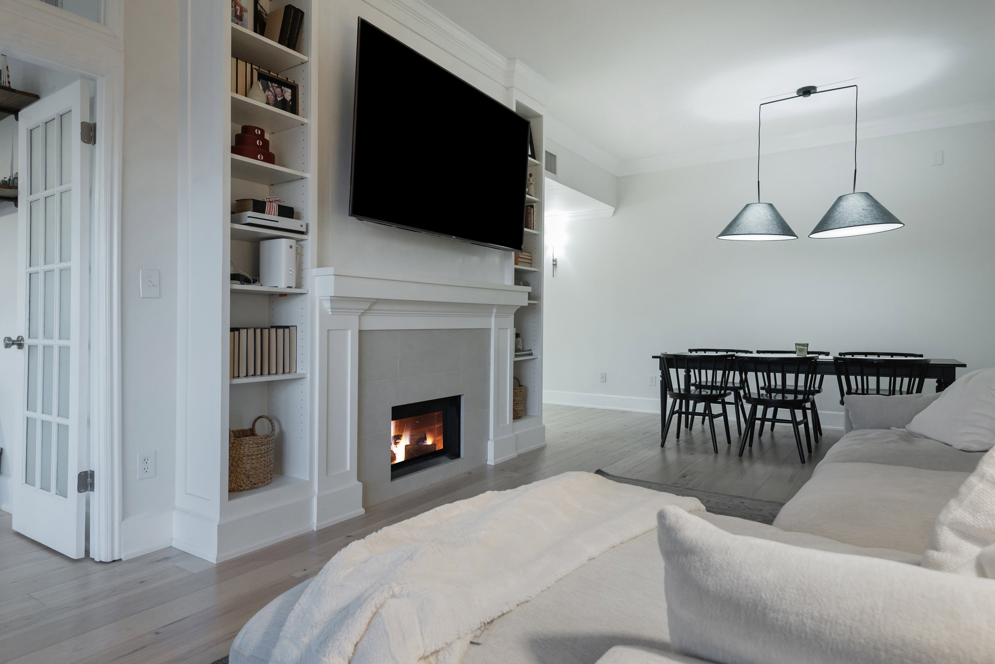 Living area with light wood finished floors, ornamental molding, a tile fireplace, and built in shelves