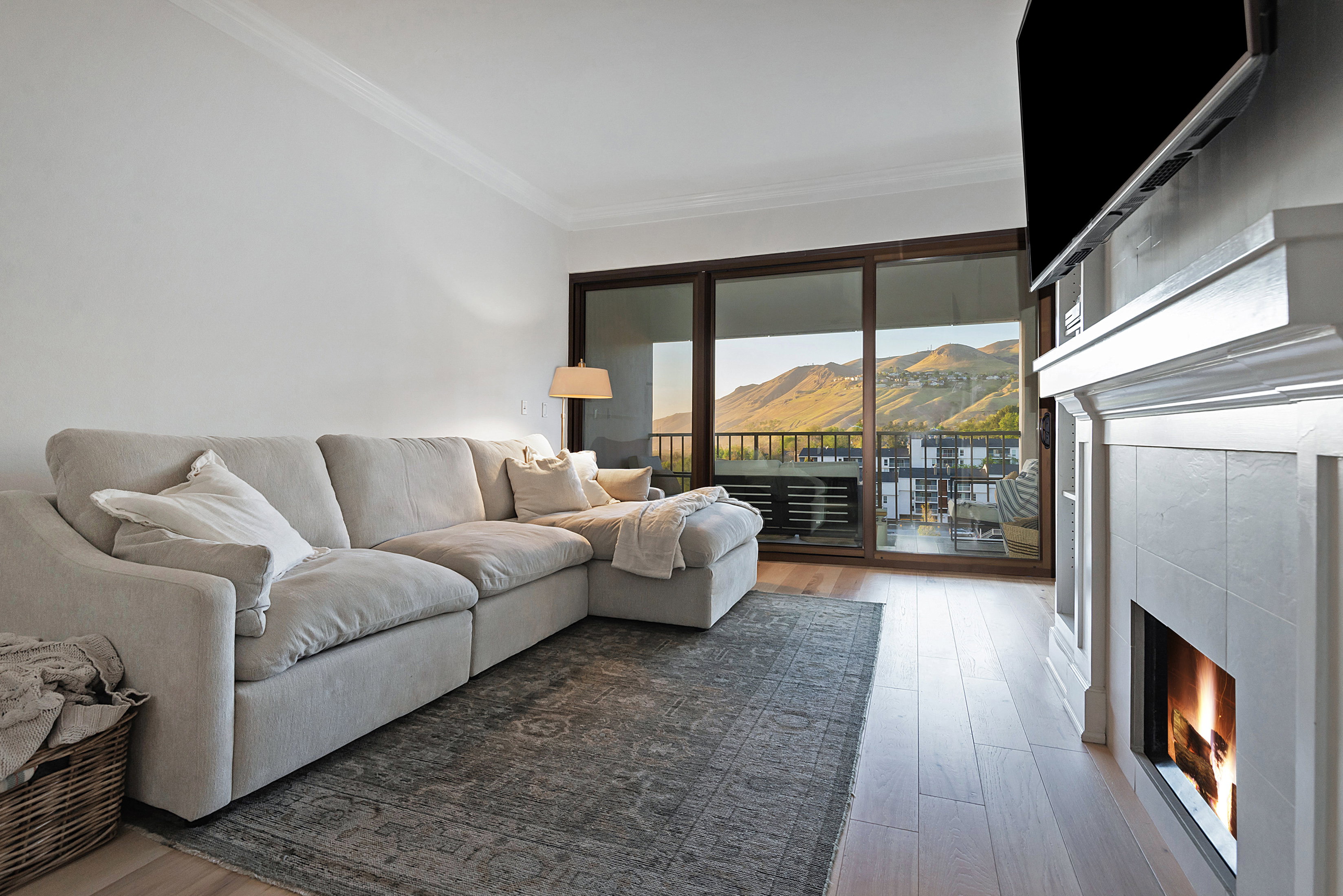 Living area featuring a tile fireplace, light wood-style floors, and crown molding