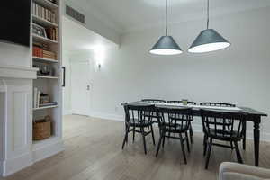 Dining space with crown molding and light wood-style flooring