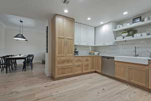 Kitchen with light wood-type flooring, tasteful backsplash, open shelves, dishwasher, and ornamental molding