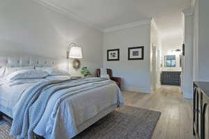 Bedroom featuring light wood finished floors, crown molding, and washer / dryer