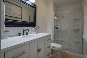 Full bathroom with vanity, a stall shower, and light wood-style flooring