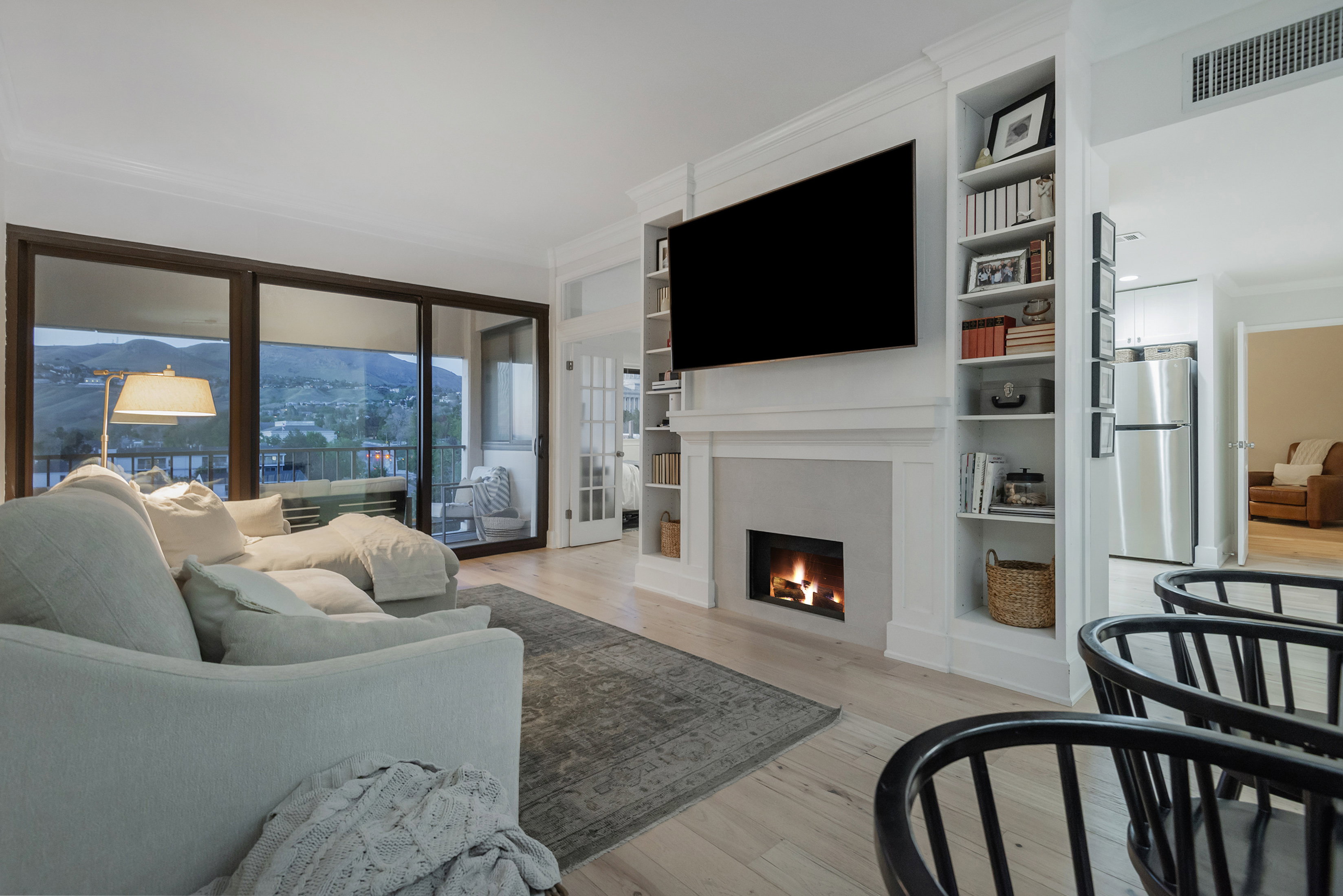 Living area with light wood-style floors, crown molding, a lit fireplace, and built in shelves