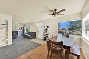 Dining space featuring built in features, light wood-style flooring, a textured ceiling, ceiling fan, and light carpet