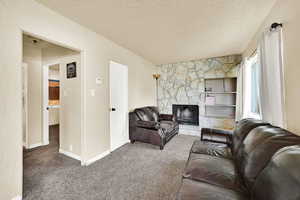 Carpeted living room featuring a fireplace and a textured ceiling