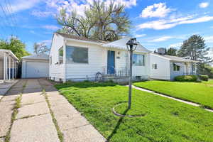 Bungalow with an outdoor structure, a detached garage, a front lawn, and driveway