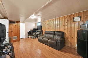 Living room with an office area, wood finished floors, and wooden walls