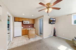 Kitchen with white appliances, light colored carpet, ceiling fan, recessed lighting, and wood finish cabinetry