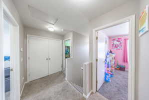 Corridor featuring an upstairs landing, light carpet, and a textured ceiling