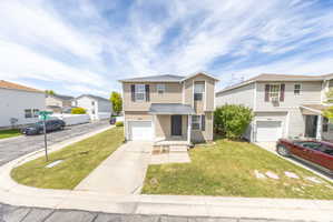 View of front of home with a front yard, an attached garage, concrete driveway, and a residential view