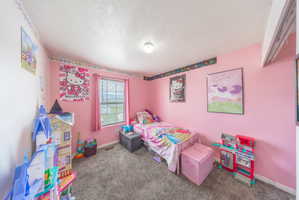 Bedroom featuring dark carpet and a textured ceiling