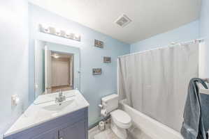Bathroom featuring vanity, shower / bathtub combination with curtain, and a textured ceiling