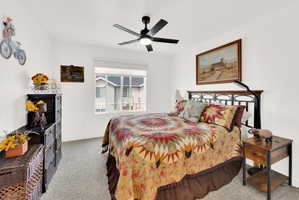 Carpeted bedroom with a ceiling fan and baseboards