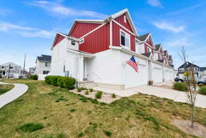 View of side of home featuring a residential view, driveway, board and batten siding, a yard, and an attached garage