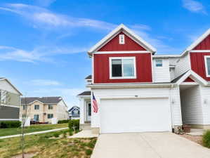 Traditional-style house with an attached garage, concrete driveway, board and batten siding, and a residential view