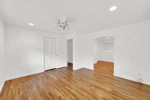 Unfurnished bedroom featuring recessed lighting, light wood-style floors, a ceiling fan, a closet, and arched walkways