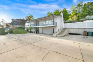 Back of property with an attached garage, a chimney, driveway, and a balcony