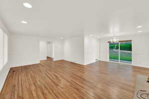 Empty room with light wood finished floors and suspended lighting