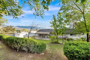 Back of house featuring a fenced backyard, a patio, a mountain view, and a chimney