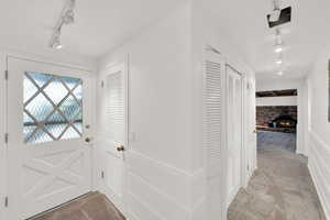 Doorway with rail lighting, carpet flooring, and a brick fireplace