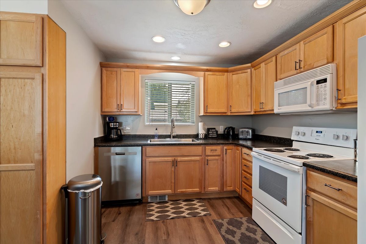 Kitchen with white & stainless appliances, LVP flooring, and recessed lighting