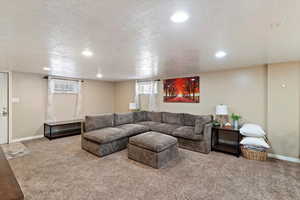 Living area with a textured ceiling, carpet flooring, and recessed lighting, and exterior door