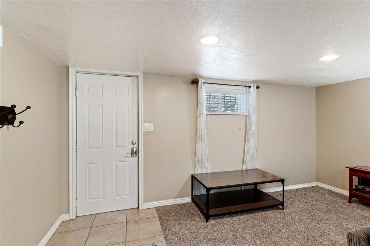 Basement exterior entry door, foyer with a textured ceiling and light tile flooring