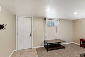 Basement exterior entry door, foyer with a textured ceiling and light tile flooring
