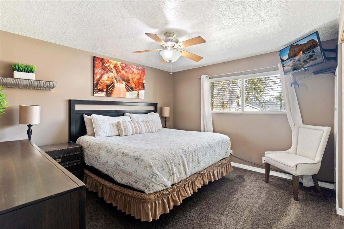 Bedroom featuring dark colored carpet, a textured ceiling, and a ceiling fan