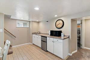 Kitchen featuring white cabinetry, a textured ceiling, stainless steel refrigerator, full-size sink, tiled floors, and recessed lighting