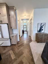 Kitchen with high end white fridge, light stone countertops, tasteful backsplash, hardwood herringbone floors