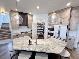 Kitchen featuring decorative backsplash, hardwood herringbone floors, light stone counters, and a breakfast bar