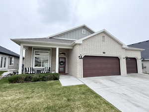 View of front of property with a garage, covered porch, board and batten siding, driveway, and a front yard