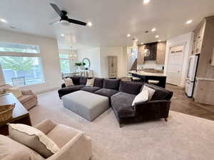 Carpeted living room with ceiling fan and hanging lights