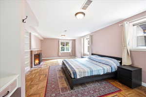 Bedroom featuring a fireplace, parquet flooring, and multiple windows