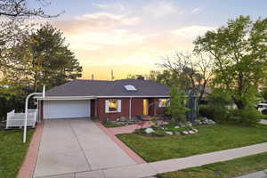 Ranch-style house featuring brick siding, a front lawn, driveway, an attached garage, and a shingled roof