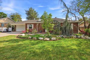 Ranch-style home featuring brick siding, a garage, a front lawn, driveway, and roof with shingles