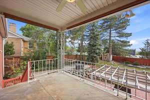 Covered porch featuring a fenced backyard, ceiling fan, and a storage unit