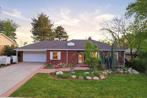 Ranch-style house with a garage, driveway, brick siding, and a chimney