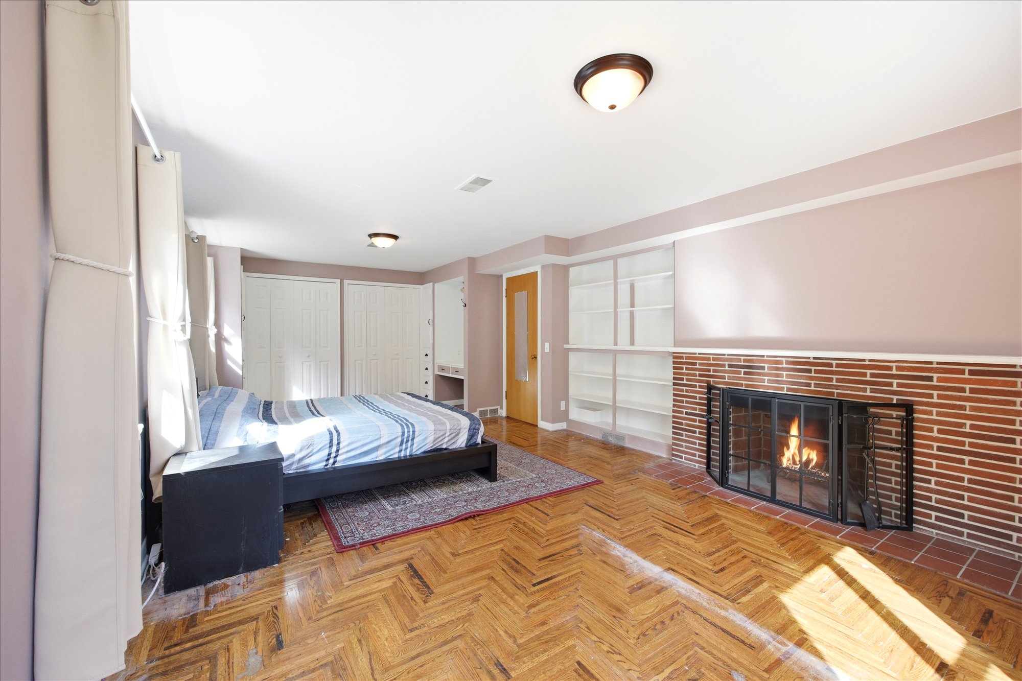 Bedroom featuring two closets, a brick fireplace, and parquet flooring