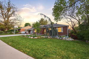 View of front of property with a front lawn, brick siding, driveway, and a chimney