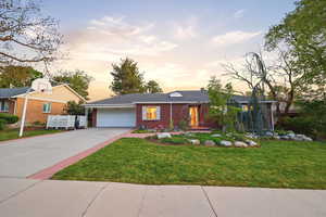 Single story home with brick siding, driveway, an attached garage, and a yard