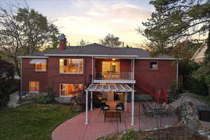 Back of property with a balcony, a patio area, brick siding, and a chimney