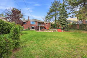 Back of property featuring brick siding, a patio area, a balcony, and a chimney