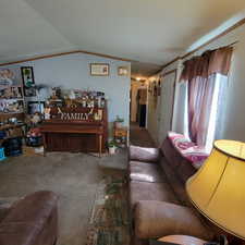 Carpeted living area featuring lofted ceiling