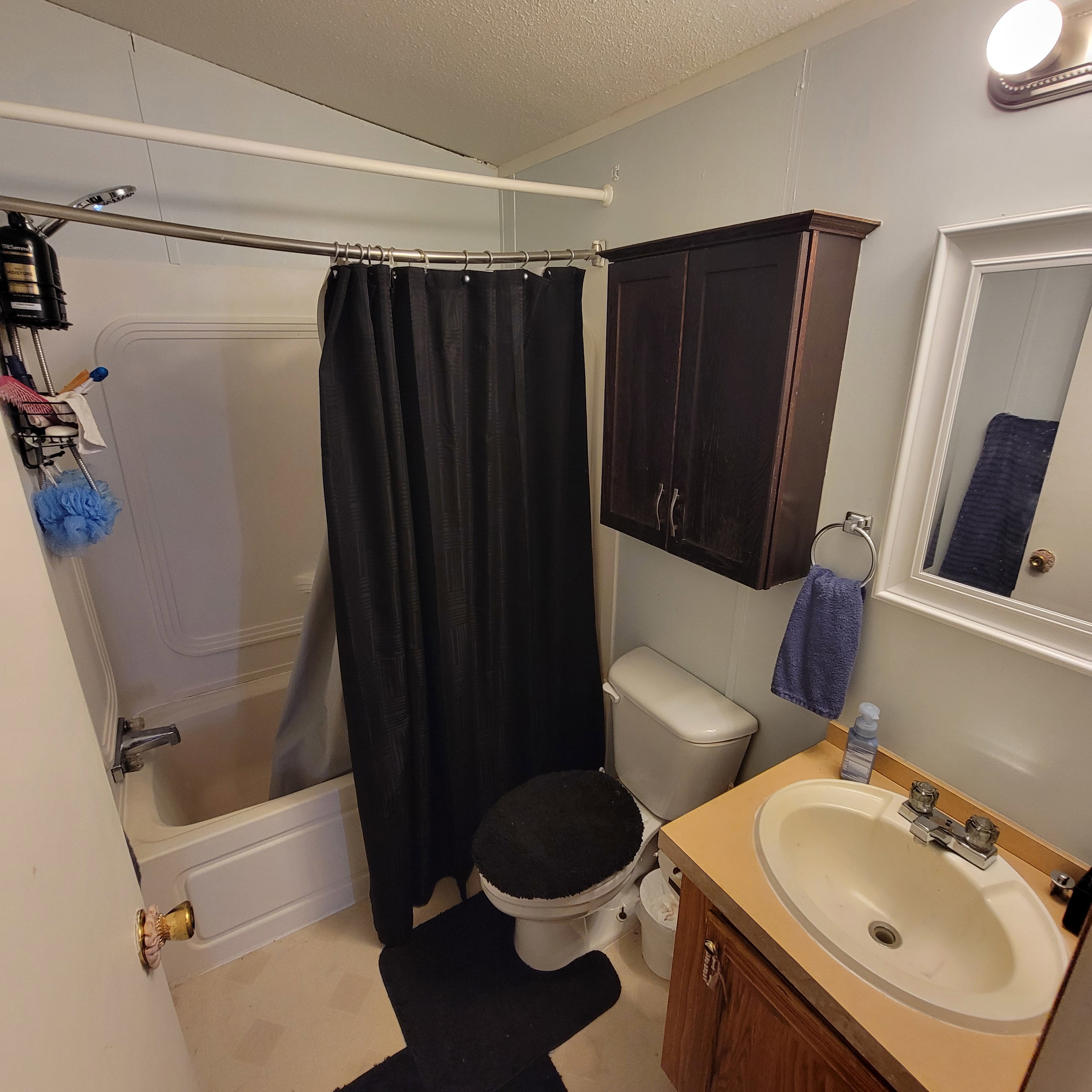 Bathroom featuring vanity, a textured ceiling, and shower / bath combination with curtain