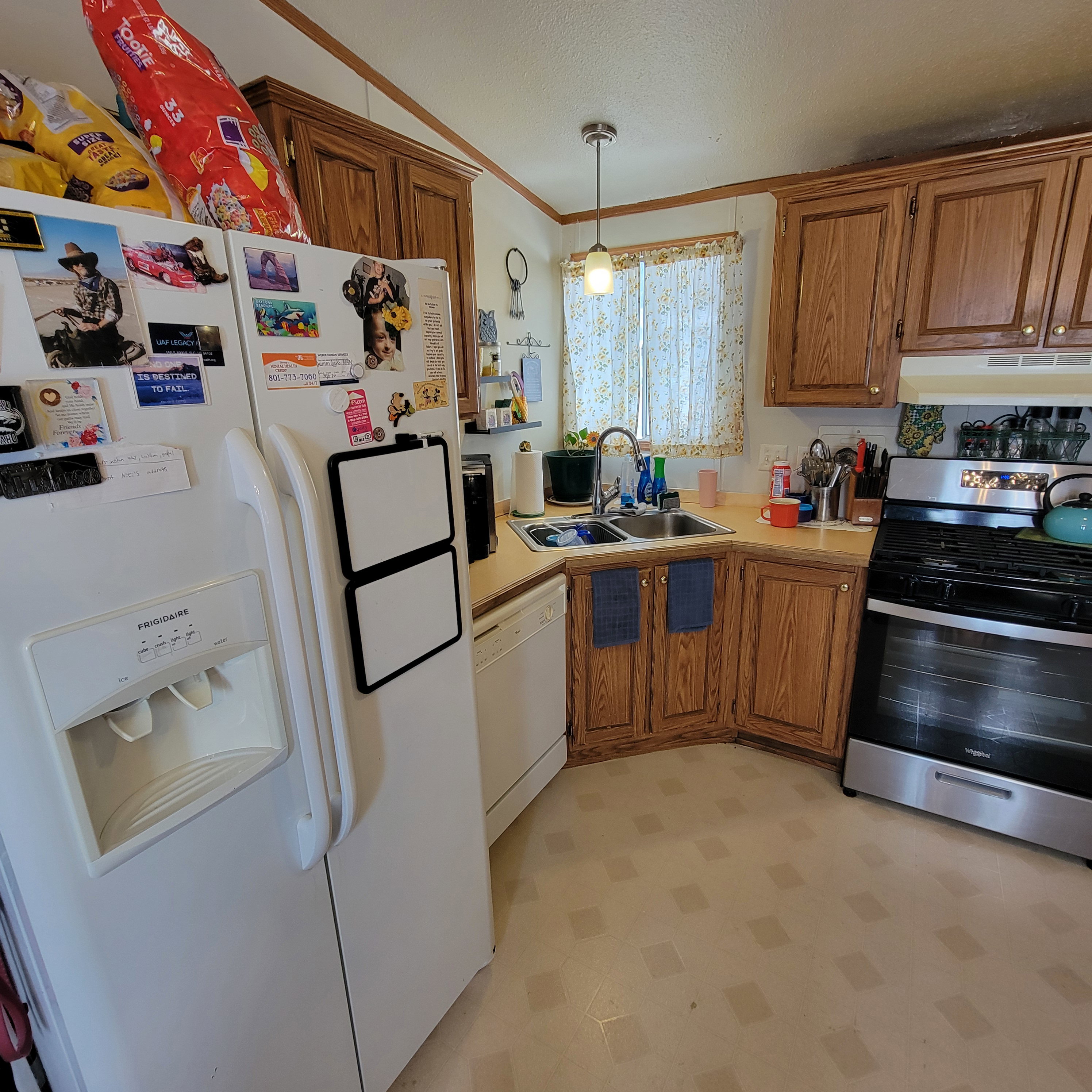 Kitchen featuring light floors, white appliances, light countertops, pendant lighting, and wood finish cabinets