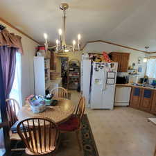 Dining room featuring crown molding, suspended lighting, vaulted ceiling, light flooring, and washer / dryer