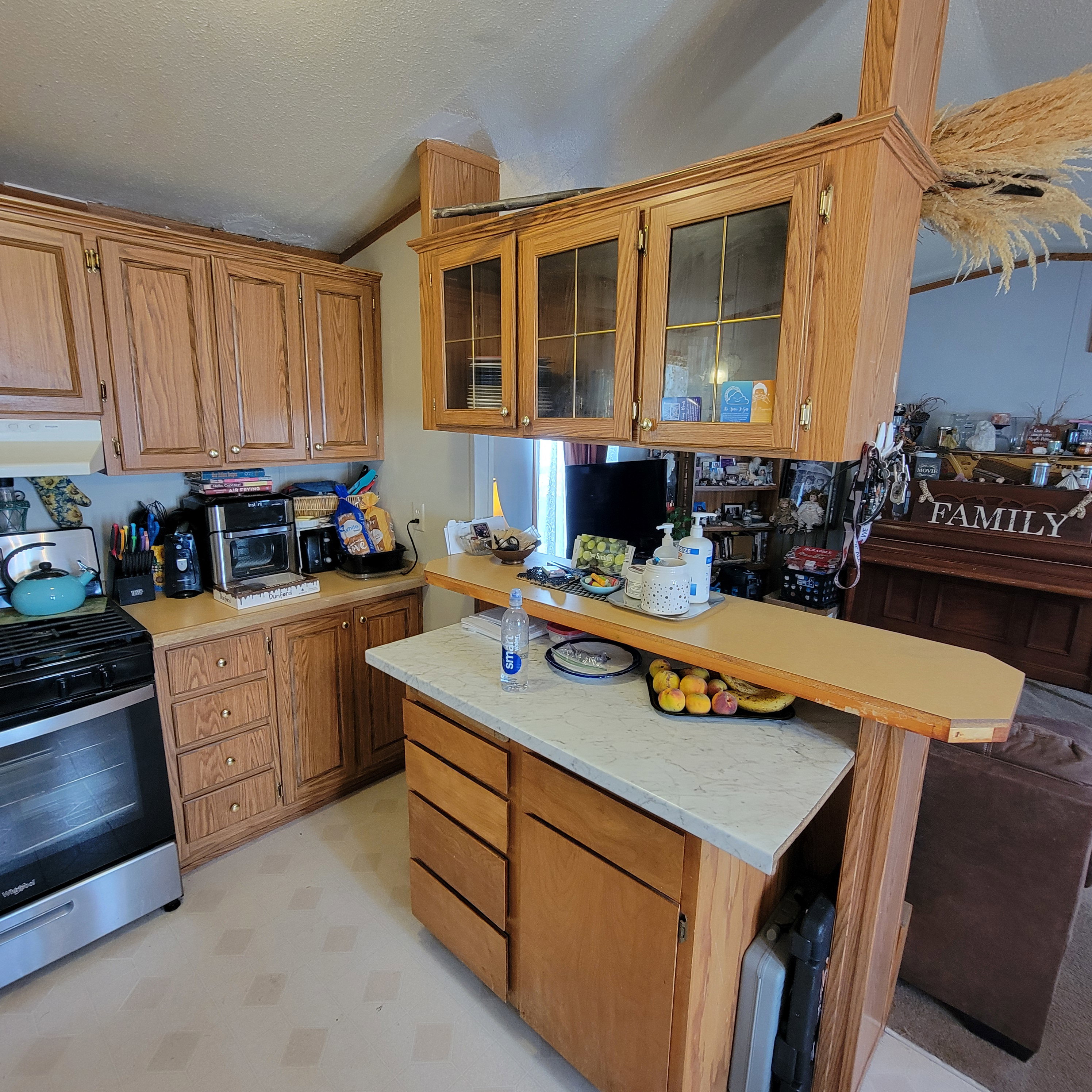 Kitchen with glass insert cabinets, light flooring, stainless steel gas range oven, and wood finish cabinets