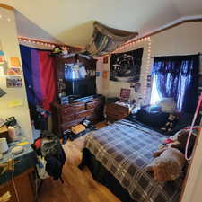 Bedroom featuring light wood-style flooring and lofted ceiling